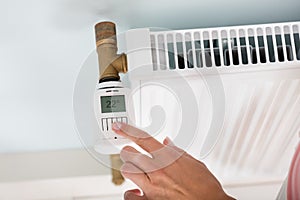 Person Adjusting Temperature On Thermostat