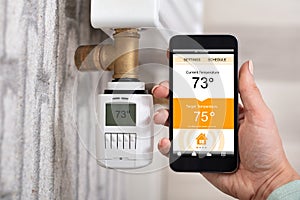 Person Adjusting Temperature Of Thermostat Using Cellphone