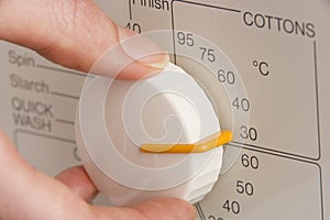 Person Adjusting Washing Machine Dial To Cold Wash