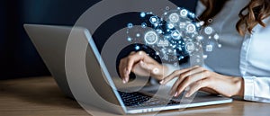 A person is analyzing data on a laptop, illuminated by screens displaying graphs and charts in a dark office setting