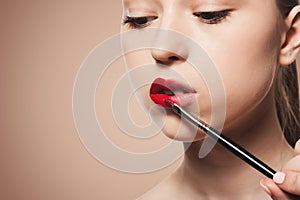 Applying Red Lipstick With a Brush for a Makeup Look in a Beauty Setting