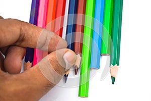 A person arranging some different colored wood pencil crayons on a white background