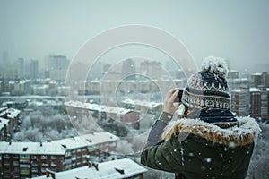 person in beanie taking pictures of snowy cityscape