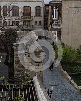 Person in Black Coat Walking among Historic Buildings in the Old Town of Baku, Azerbaijan