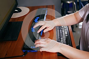 Person with blindness disability`s hands using computer with braille display or braille terminal a technology assistive device fo