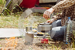 A person boiling water over a propane stove to make tea