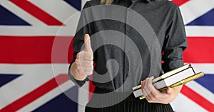 Person with books shows thumb up against UK flag