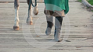 Person in boots leading a horse.