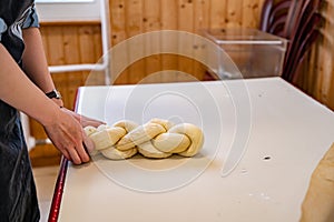 Person braiding a loaf of swiss zopf bread with their hands