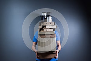 Person is carrying and delivering stack of boxes with pizzas, food and drinks