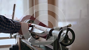 Person carving chisel candlestick on a lathe. Closeup of carpenter turning wood on a lathe.