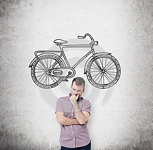 A person in casual clothes is thinking about affordable or environmental friendly ways of travelling. A sketch of bicycle is drawn