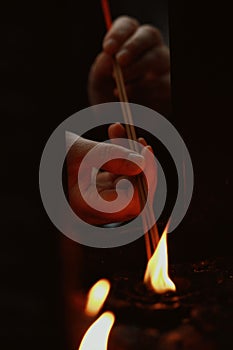 Person is ceremoniously lighting incense sticks over water in a dimly lit space