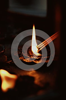 Person is ceremoniously lighting incense sticks over water in a dimly lit space