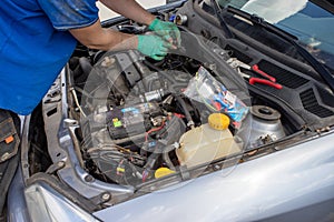 The person changes the oil filter in the car