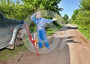 The person changes a wheel at the car by means of a red rack jack