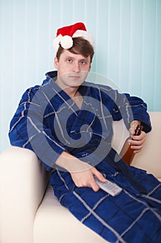 Person in christmas hat sits on sofa with beer