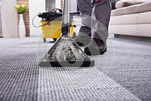 Person Cleaning Carpet With Vacuum Cleaner