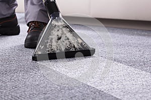 Person Cleaning Carpet With Vacuum Cleaner