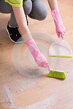 Person cleaning floor with dustpan