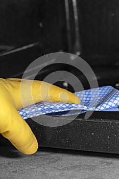 Person cleaning the inside of a microwave oven with a blue and white cloth