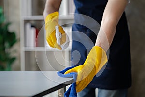 Person cleaning the room, cleaning staff is using cloth and spraying disinfectant to wipe the glass in the company office room.