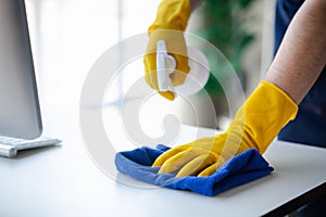 Person cleaning the room, cleaning staff is using cloth and spraying disinfectant to wipe the glass in the company office room.