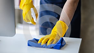 Person cleaning the room, cleaning staff is using cloth and spraying disinfectant to wipe the glass in the company office room.