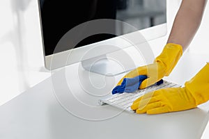 Person cleaning room, cleaning worker is using cloth to wipe computer keyboard in company office room. Cleaning staff. Concept of