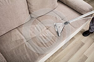 Person Cleaning Sofa With Vacuum Cleaner