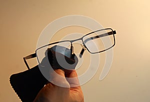 Person cleaning their black glasses with microfibre cloth