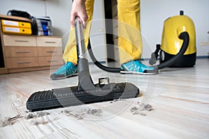 Person cleaning wooden floor with vacuum cleaner