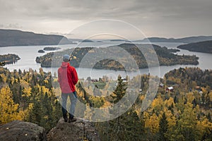 Person at cliff in Landscape panorama with islands of HÃ¶ga Kusten at the lookout point RÃ¶dklitten in Sweden in autumn