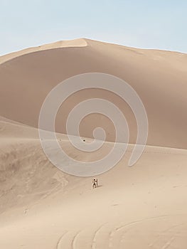 Person climbing a dune in a vast desert