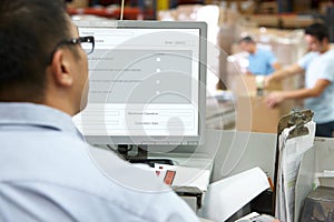 Person At Computer Terminal In Distribution Warehouse