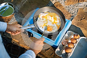 Person cooking eggs on camping stove