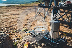 Person cooking fried eggs hot coffee in nature camping outdoor, cooker prepare scrambled omelette breakfast picnic, tourism