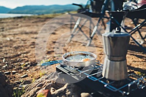 Person cooking fried eggs hot drink in nature camping outdoor, cooker prepare scrambled omelette breakfast picnic, tourism