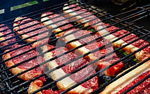 Person cooking raw steaks on a barbecue grill