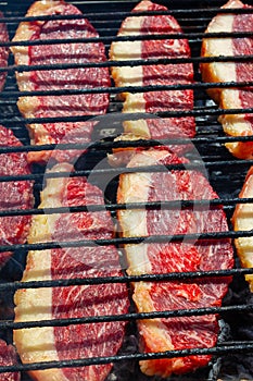 Person cooking raw steaks on a barbecue grill