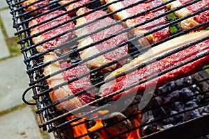 Person cooking raw steaks on a barbecue grill