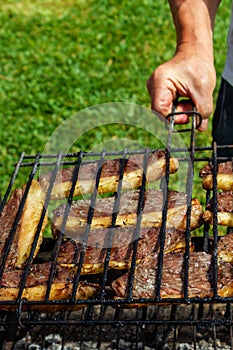 Person cooking steaks on a barbecue grill