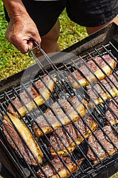 Person cooking steaks on a barbecue grill