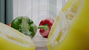 Person cuts bell pepper into half against lying vegetables