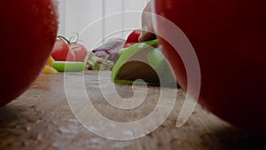 Person cuts bell pepper into pieces behind vegetables