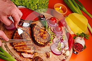 Person cuts grilled meat on cutting board