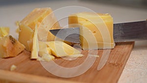 Person cuts hard cheese on wooden cutting board using knife