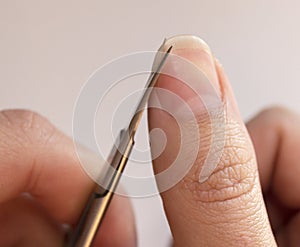 A person cuts his nails with small scissors. Men`s manicure. A man cuts off a large overgrown nail