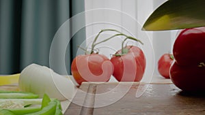 Person cuts off red bell pepper piece with green peduncle