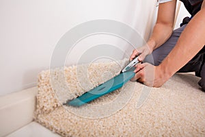 Person Cutting Carpet With Cutter photo